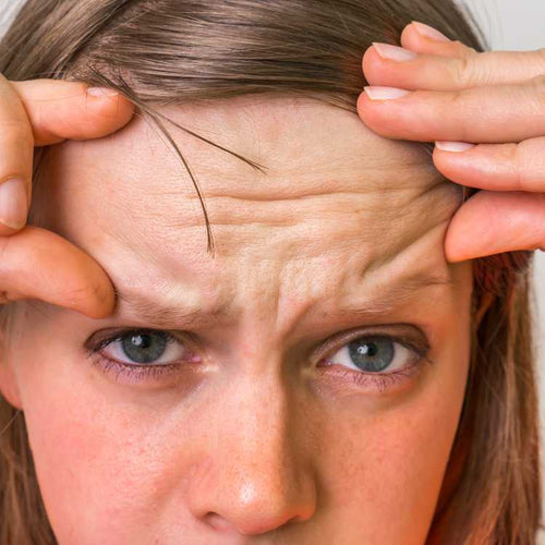 Close-up of a woman with her hands on her temples, showing signs of stress or concentration.